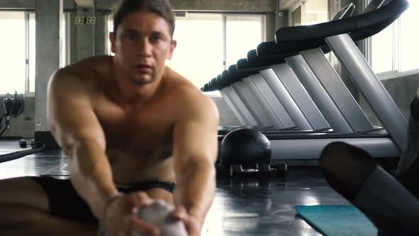 Young Woman and Man Stretching Their Legs on the Gym Floor