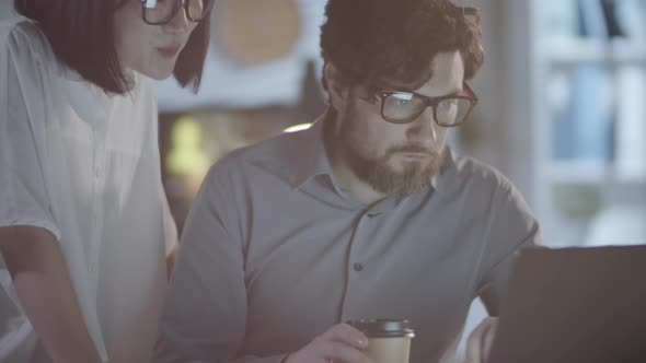 Colleagues Talking and Looking at Laptop in Dark Office