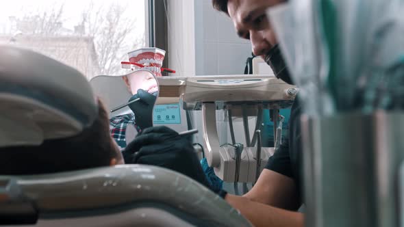 A Dentist Examines the Mouth of a Young Boy