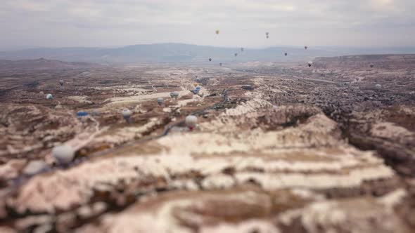 Miniature View of Rocky Valley and Flying Hot Air Balloons in Cappadocia Filmed By Drone