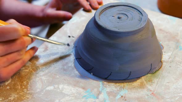 Hand of artist painting on earthenware bowl