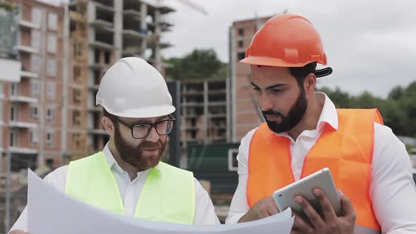 Building a Residential Complex or Business Center. Team of Engineers Men with a Tablet and Drawing