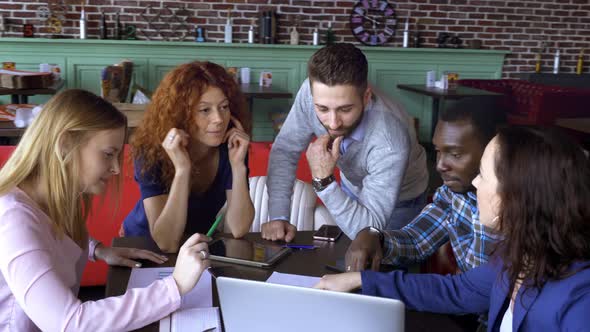 Business, Startup and People Concept - Happy Creative Team with Computers and Folder Discussing