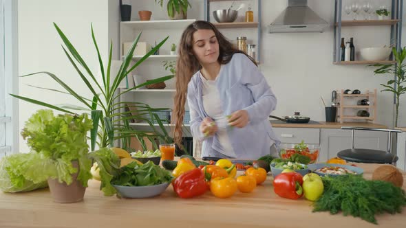 Happy Pregnant Woman Enjoying Preparing a Salad Cutting Organic Vegetables