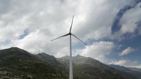 Windmills rotating in the background of mountains and cloud.