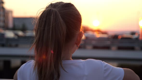 Teenage Blonde with Long Hair in Ponytail Admires Sunset