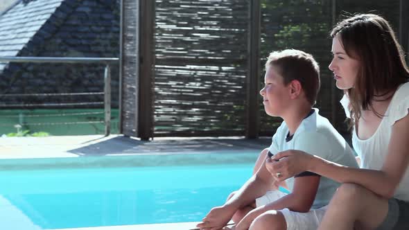 Mother and son hugging on lounger by pool