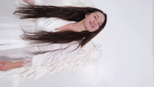 Young Brunette Girl with White Wings on a White Background the Image of a Holy Angel