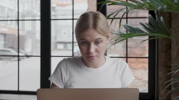 Thoughtful concerned woman working on laptop computer looking away thinking solving problem