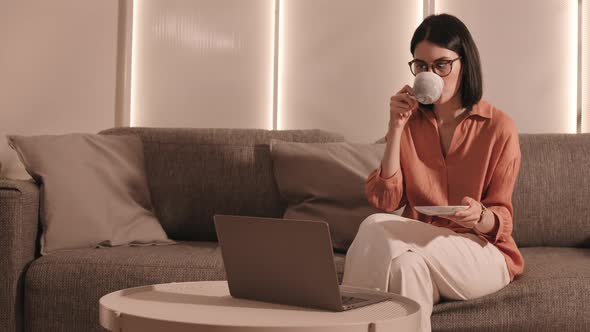 Woman Drinking Tea and Using Laptop
