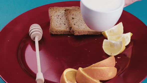 A Man's Hand Rests a Cup of Fresh Yogurt on a Rotating Red Plate