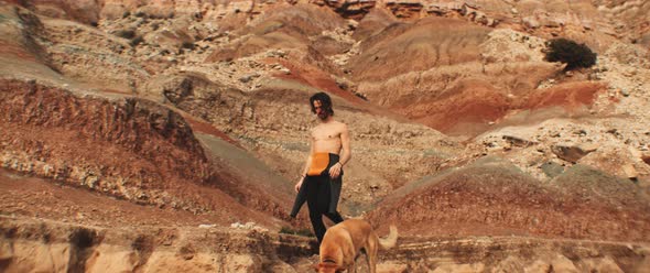 Surfer walking down a rocky hill with his dog