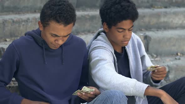 Poor homeless african american male friends counting money