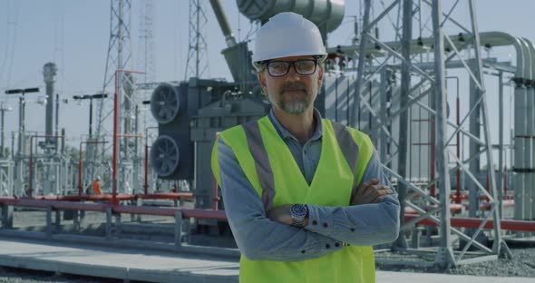 Mature Foreman Crossing Arms on Power Plant