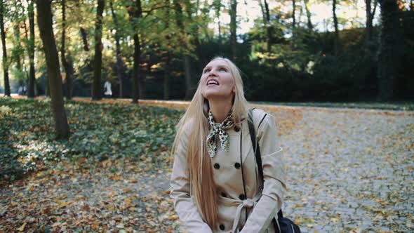 Young Girl Walking in Autumn Park and Throwing Golden Leaves in the Air, Slow Motion