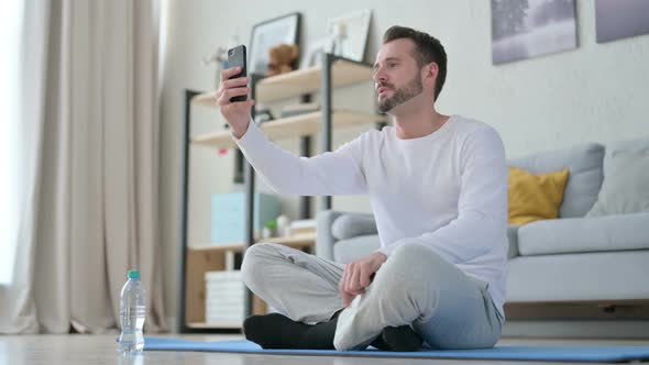 Man Talking on Video Call on Smartphone on Yoga Mat