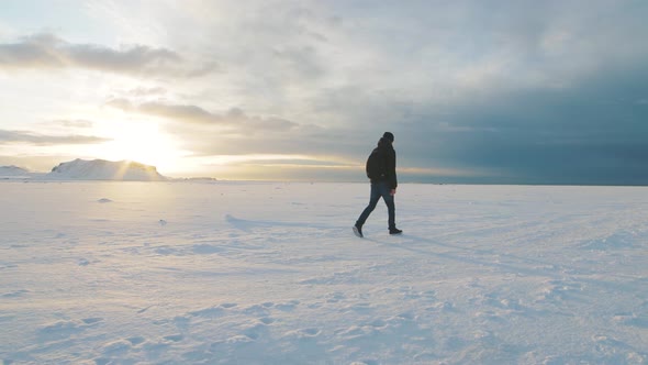 Man Traveler Walking on Snow Desert in Iceland