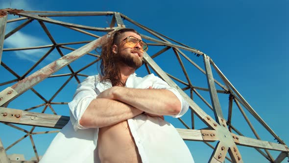 Masculine Smiling Man with Naked Torso Standing with Crossed Hand Posing at Blue Sky Grid Background