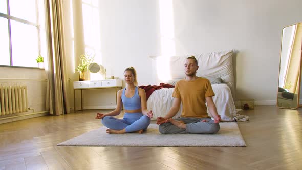 Footage of a Young Couple Meditating at Home Together