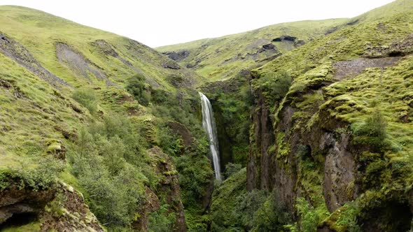 Idyllic View Of Narrow Canyon And Mystic Waterfall In Iceland - aerial shot