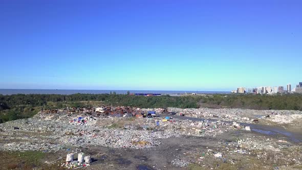 Drone view of city dump on background of sea, the city and the mountains.