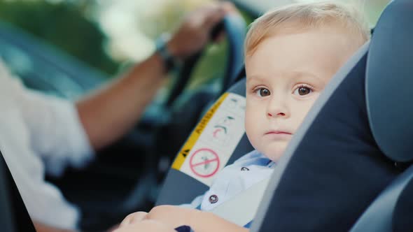 Portrait of a Cute Little Boy Boy, Sits in a Children's Car Seat Near the Pope. Safety and Child