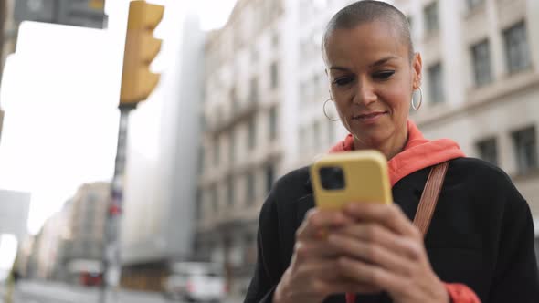 Happy bald woman texting by phone