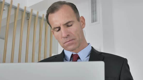 Pensive Middle Aged Businessman Thinking and Working on Laptop