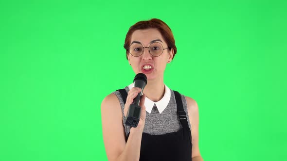 Portrait of Funny Girl in Round Glasses Is Singing Into a Microphone and Moving To the Beat of Music