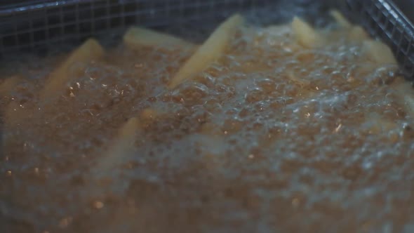 French Fries Fried in a Wire Basket in Hot Oil