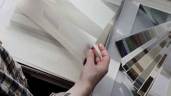 Woman fliping through catalog with roller blinds or window shade.