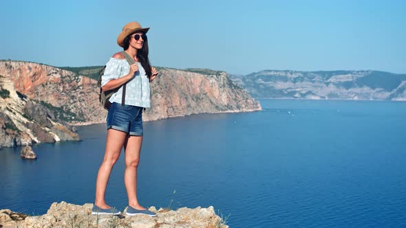 Charming Travel Backpacker Woman Standing on Top of Mountain Admiring Beautiful Sea Landscape