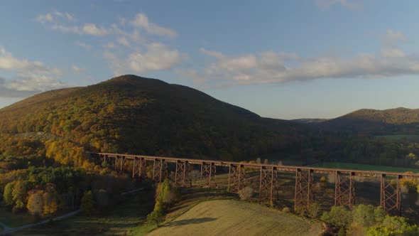 Aerial of railroad bridge passing over valley landscape between mountains