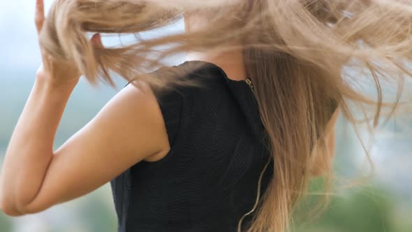 Closeup of Long Free Falling Female Hair Waving on Light Wind on Her Shoulders Outdoors