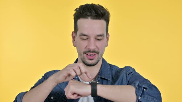 Portrait of Professional Young Man Using Smartwatch, Yellow Background