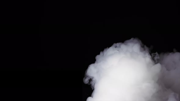 White Smoke Slowly Spreads Over a Black Surface