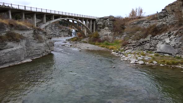 Slow motion aerial shot approaching an old arch bridge near Lundbreck falls in southern Alberta, Can