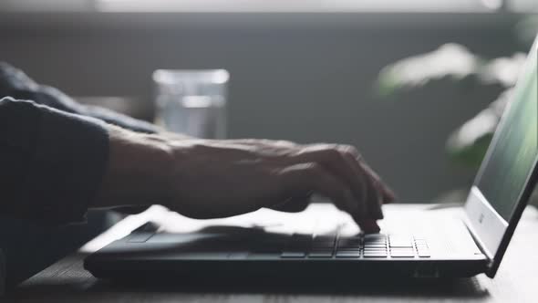 An Unrecognizable Man is Typing Very Quickly on a Laptop Keyboard