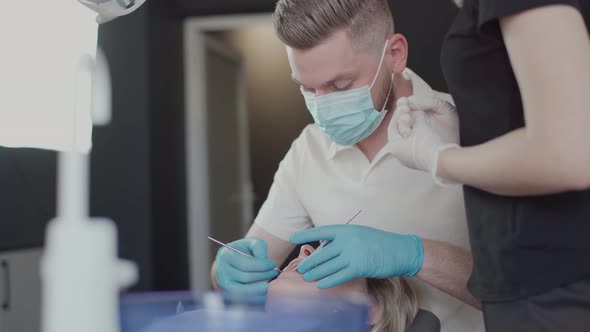 Two dentists, a man and a woman in protective masks and medical gloves