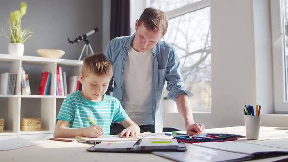 Boy and Father Doing Homework at the Table. Child is Learning at Home.