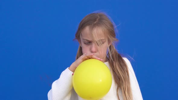 Close Up of a Cheerful Girl Inflating a Yellow Balloon