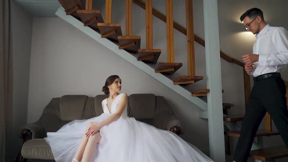 Bride helps groom get dressed and prepare for wedding ceremony. Slow motion