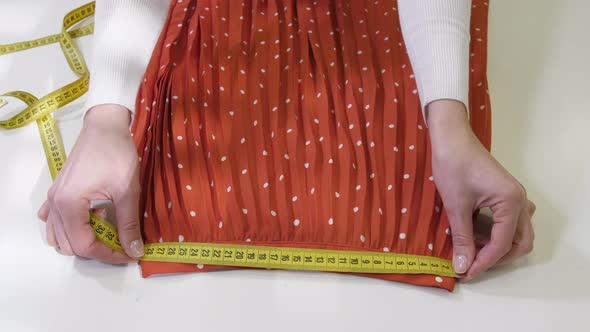 Hands Measuring Pleated Skirt Before Dry-cleaning