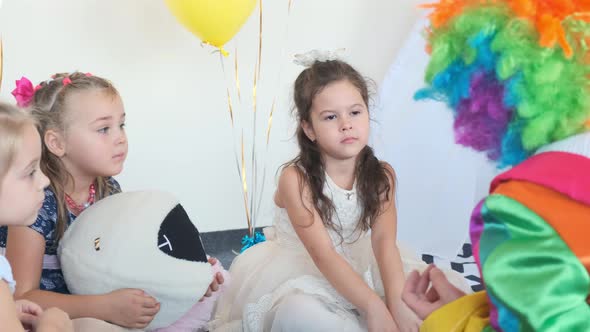 Girls with Clown in Rainbow Wig Sit on Floor at Birthday