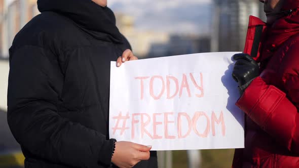 Two Unrecognizable Caucasian Women with Freedom Today Banner Outdoors on Sunny Spring Autumn Day