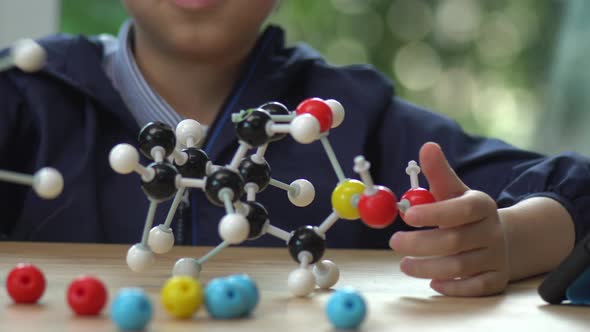 Close Up Of Asian Child Constructing Molecular Model  In Science Classroom