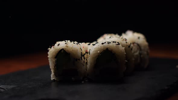 Portion of White and Black Sesame Sprinkled Rolls with Cucumber and Salmon in a Changing Light on a