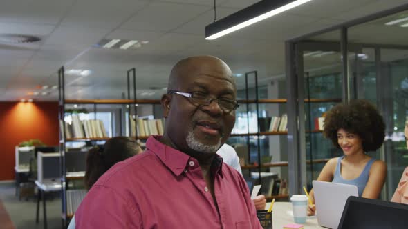 Portrait of african american businessman smiling over diverse business colleagues talking