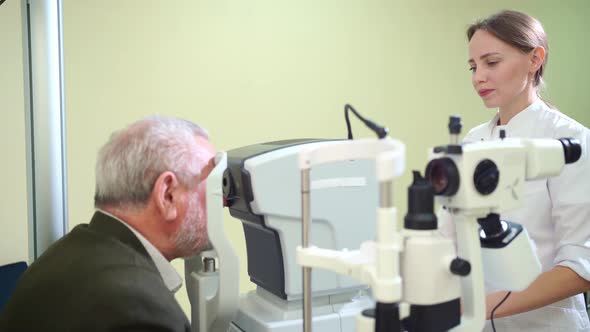 Doctor Examines Elderly Man's Eye on Screen of Autorefractometer