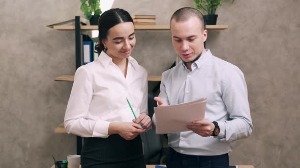 Manager Looks at Documents From Junior Employee in Office